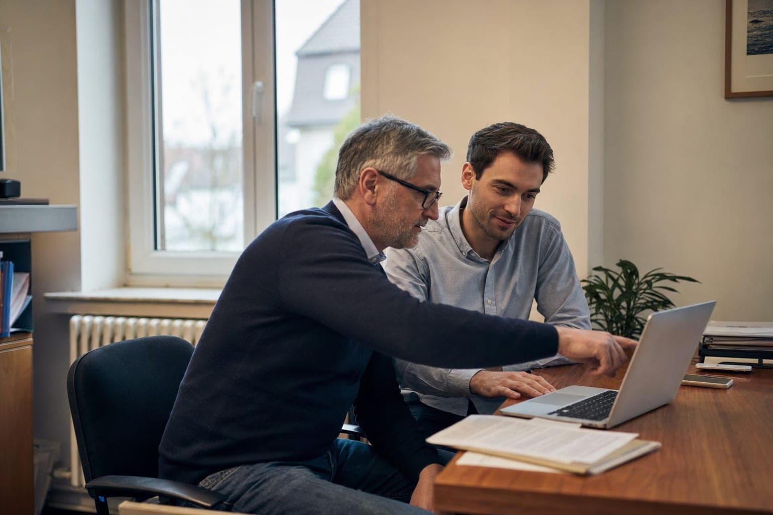 Zwei Personen im Büro besprechen am Laptop die offene Stelle